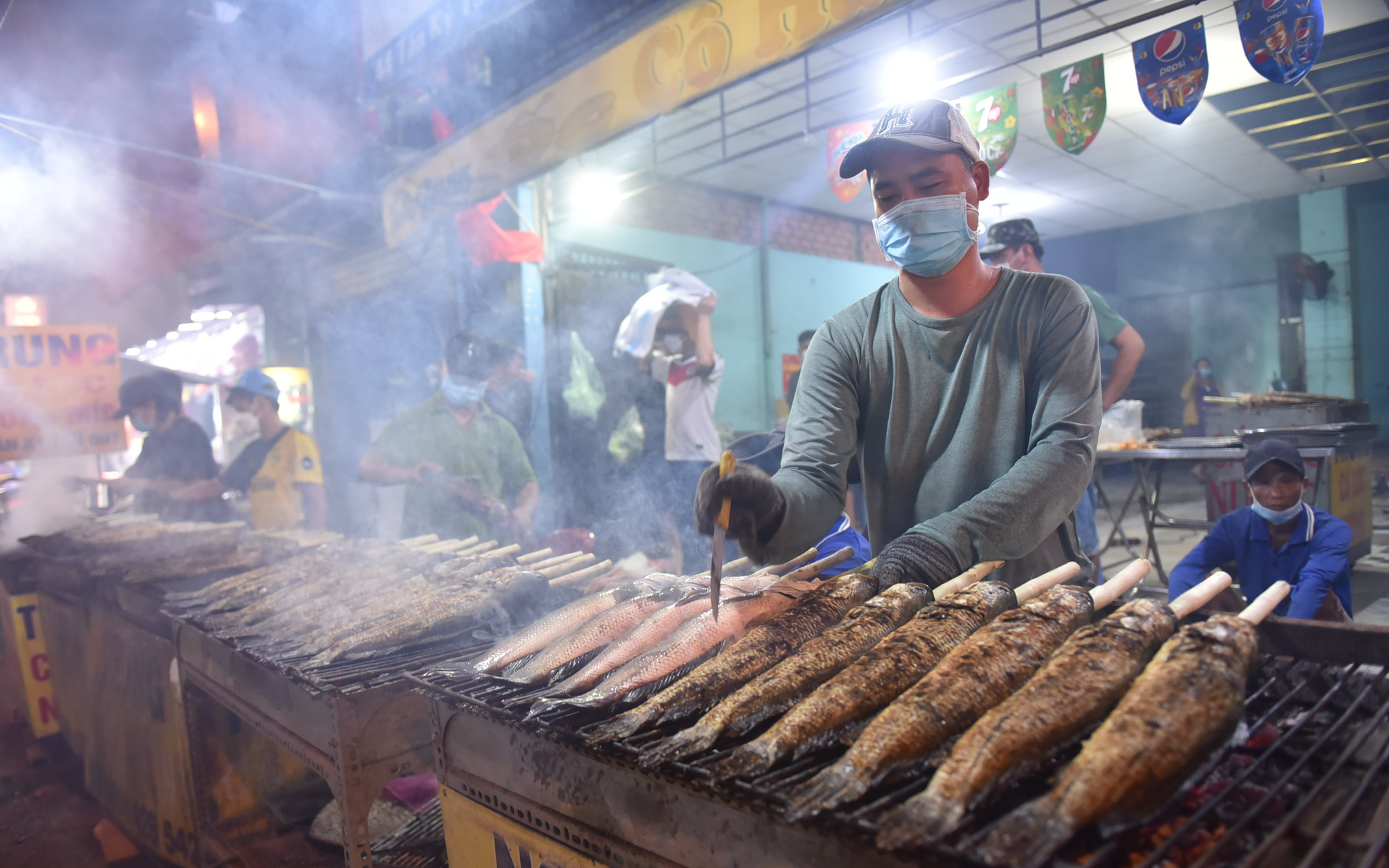 Ngày vía Thần Tài: Đổ xô mua cá lóc nướng, có gian hàng đã bán hơn 3.000 con- Ảnh 10. Đỏ lửa nướng gần 3.000 con cá lóc trước ngày vía Thần Tài