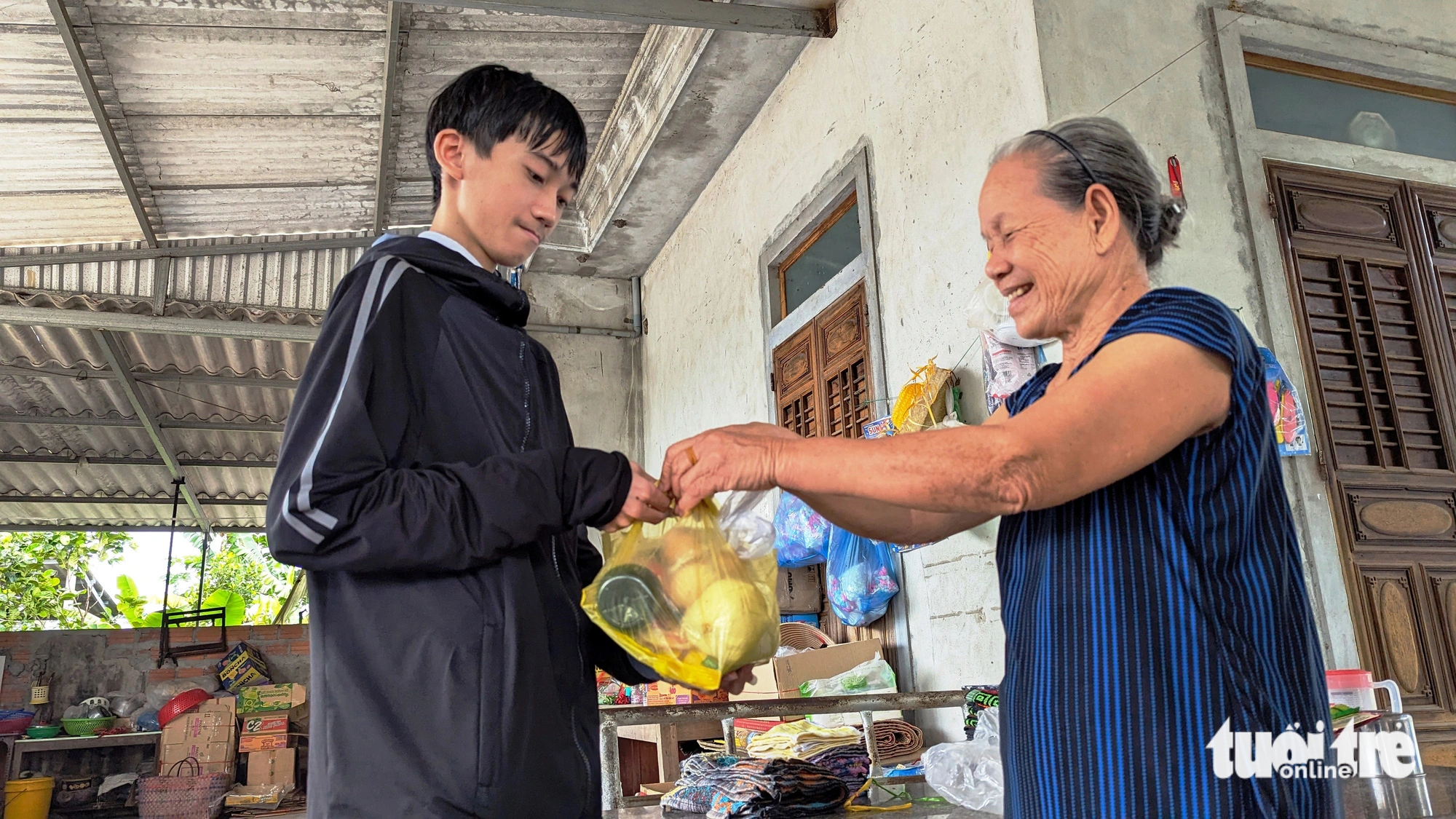 Hay tin Sinh trúng tuyển vào đại học, hàng xóm láng giềng ai cũng mừng. Bà Huỳnh Thị Thơ (hàng xóm của Sinh) gói ghém gửi cho cậu tân sinh viên nghèo quả trứng gà, chai xì dầu đem lên phố - Ảnh: NHẬT LINH