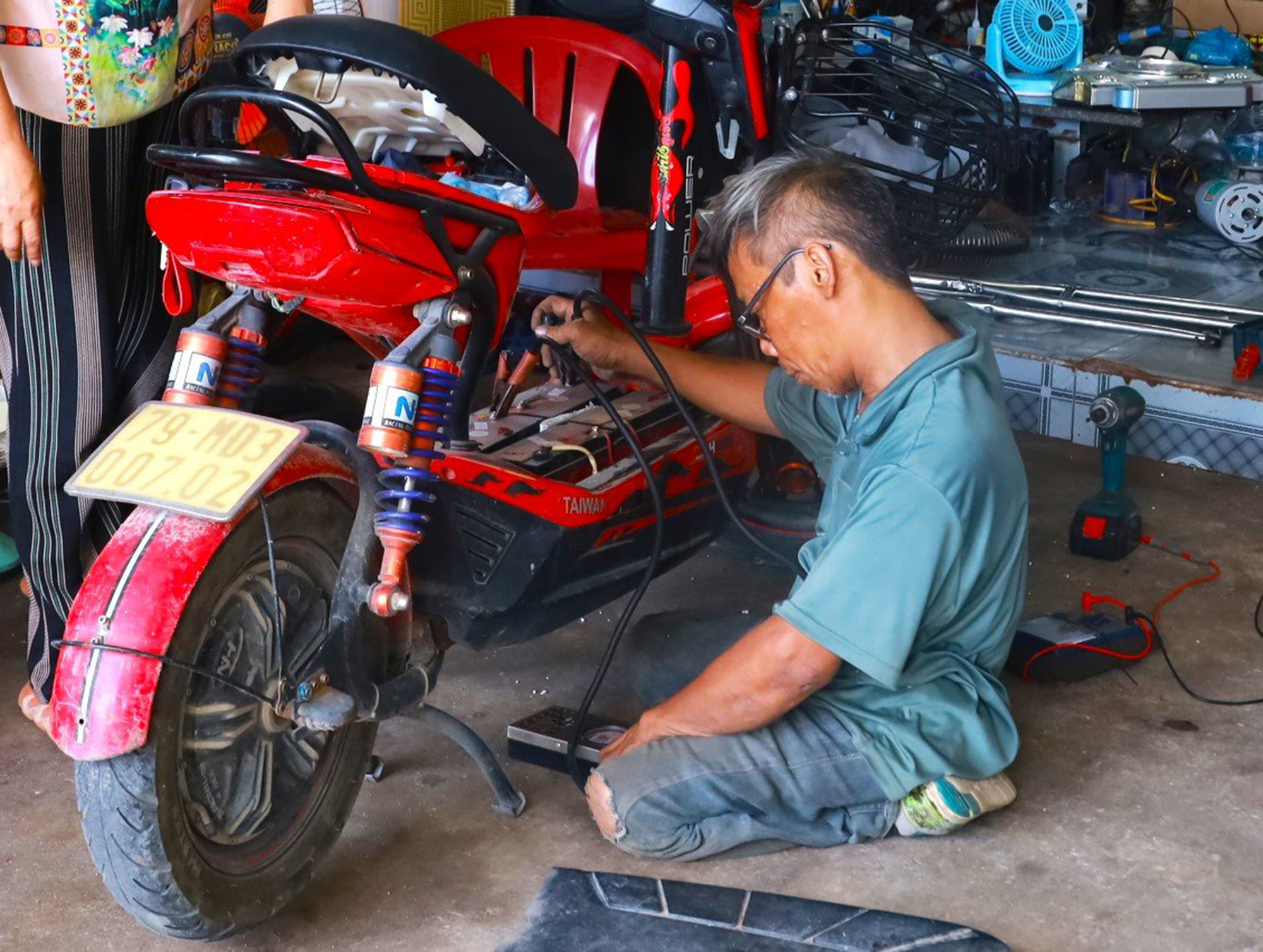 Mr. Nguyen Van Singh repairing the battery of a student's electric bicycle - Photo: Hoang Duong