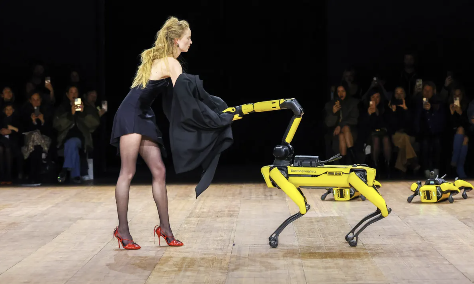 Robot Spot đang cởi áo khoác giúp một nữ người mẫu - Ảnh: GETTY IMAGES