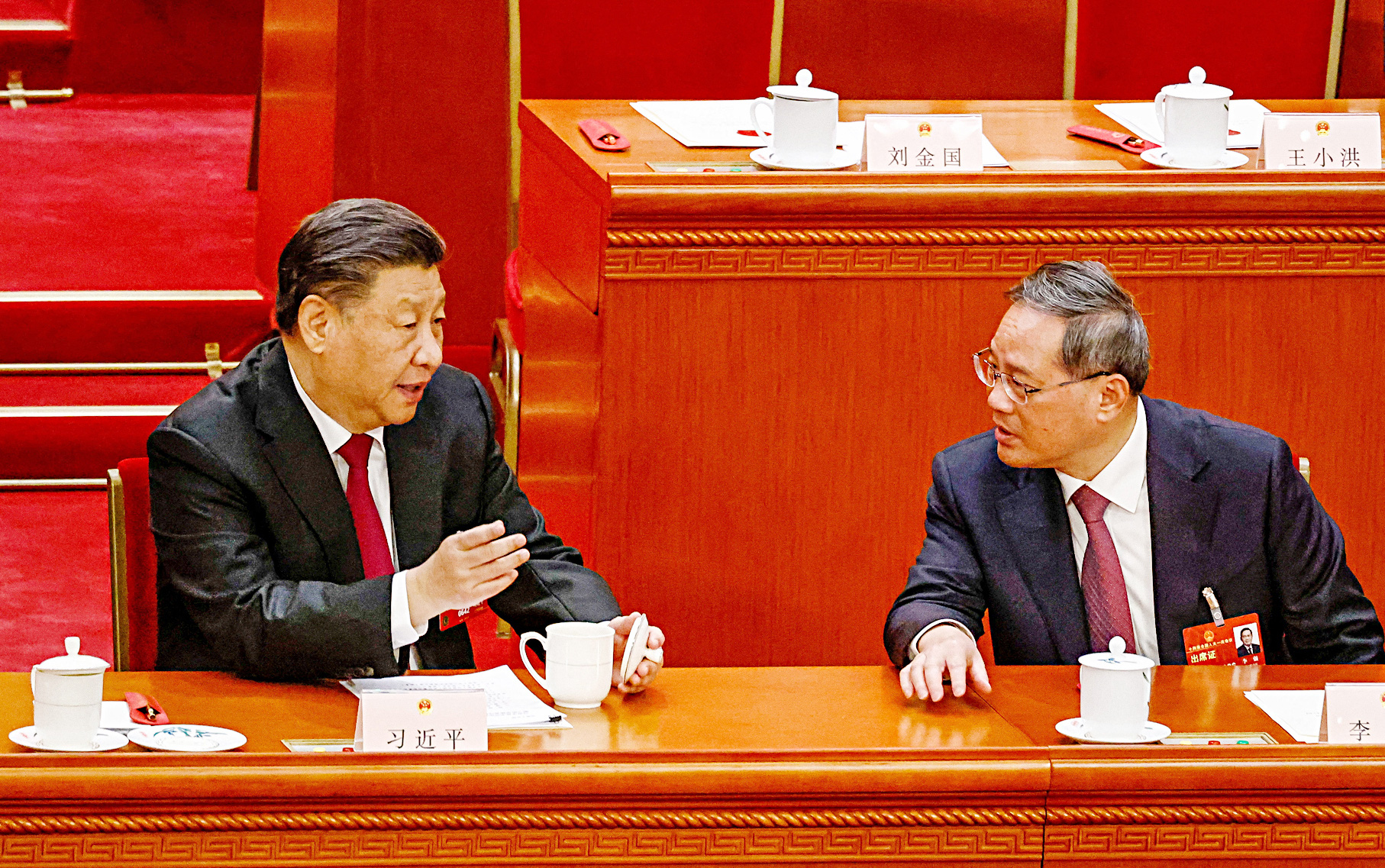 Chinese President Xi Jinping talks with Li Qiang, who is expected to become prime minister, at the 14th National People's Congress session in Beijing on March 10.  In front of Mr. Xi are two cups of tea, while Mr. Li has only one - Photo: Reuters
