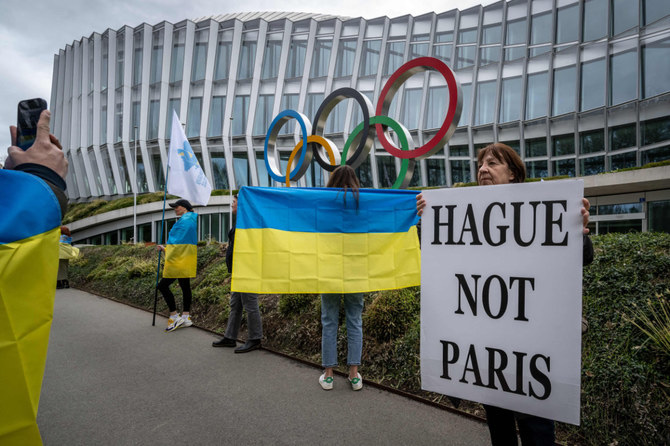 Những người Ukraine cầm biểu ngữ trong cuộc biểu tình hôm 25-3 trước trụ sở chính của IOC tại Lausanne, Thụy Sĩ nhằm phản đối việc cho phép các vận động viên người Nga quay trở lại thi đấu - Ảnh: AFP
