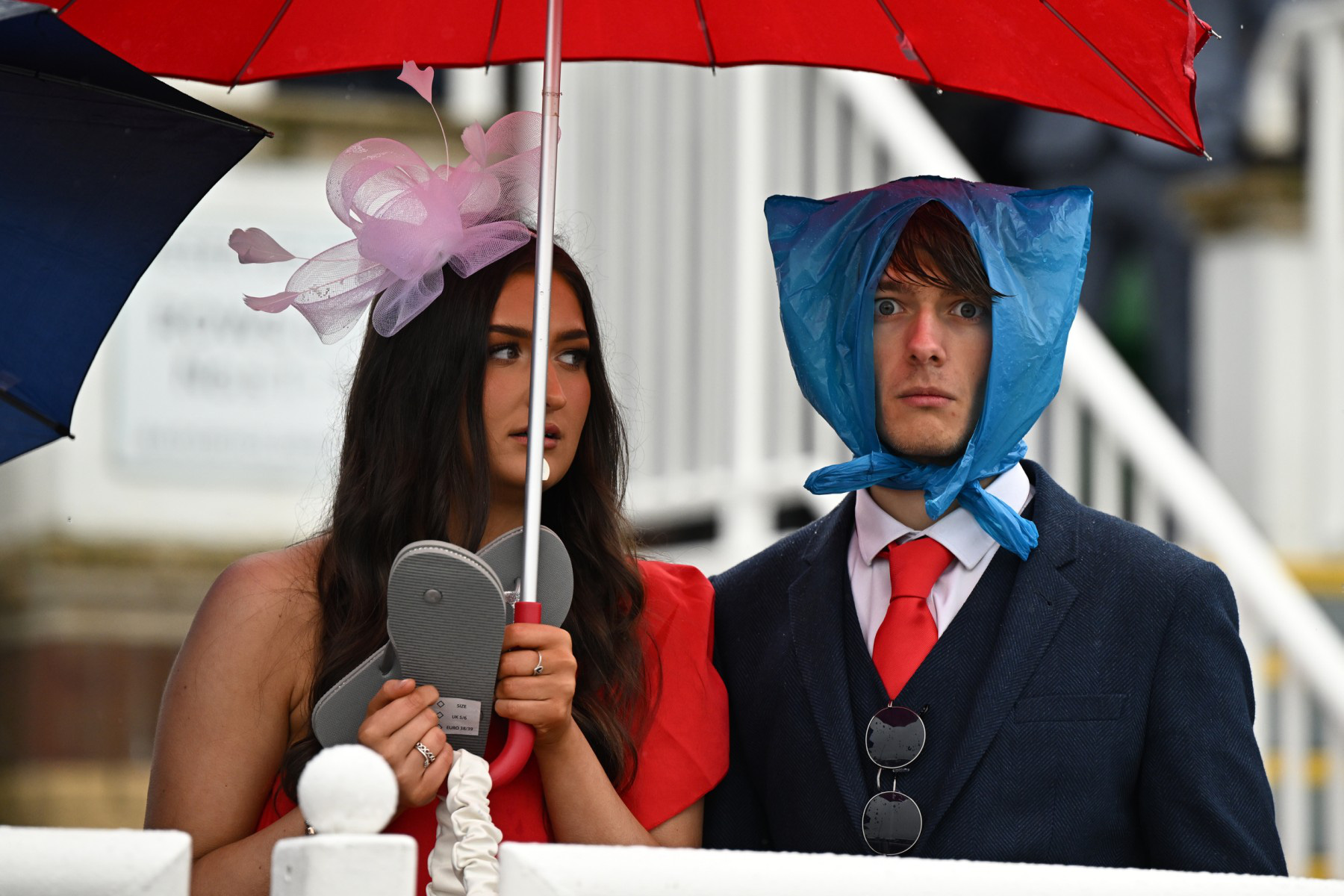 ผู้เข้าร่วมการแข่งขันม้าในเทศกาล Grand National Festival แสดงความคิดสร้างสรรค์ท่ามกลางสายฝนที่สนามแข่งม้า Aintree ในลิเวอร์พูล ทางตะวันตกเฉียงเหนือของอังกฤษ เมื่อวันที่ 14 เมษายน - รูปภาพ: AFP