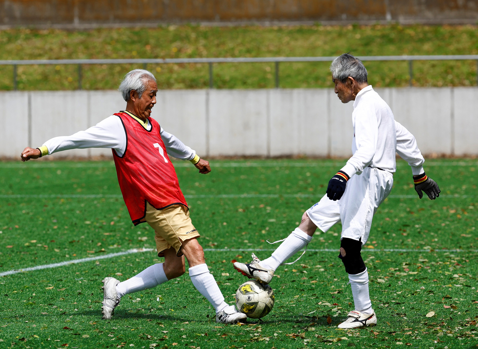 写真は80リーグSFL（サッカー）の開幕戦で、レッドスターチームの83歳MF野村睦彦選手（左）とグリーンハワイアンチームの87歳ゴールキーパー西野浩志選手がボールを奪い合う。 For Life) 選手のためのサッカー大会。  4月12日、東京の80歳以上の選手 - 写真: ロイター