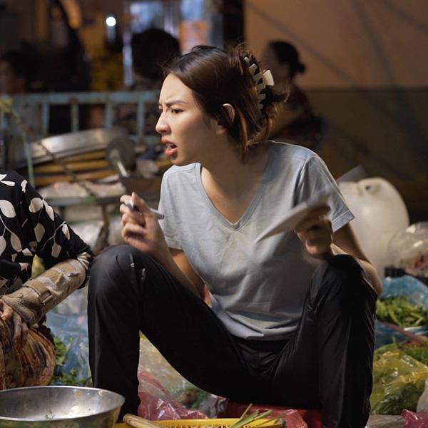Hoa hậu Thùy Tiên để mặt mộc, ăn mặc giản dị khi trải nghiệm công việc bán rau trong dự án &quot;Đu đêm&quot; do cô lên ý tưởng thực hiện. Biểu cảm cùng dáng ngồi 'bá đạo' của người đẹp khiến khán giả phì cười.