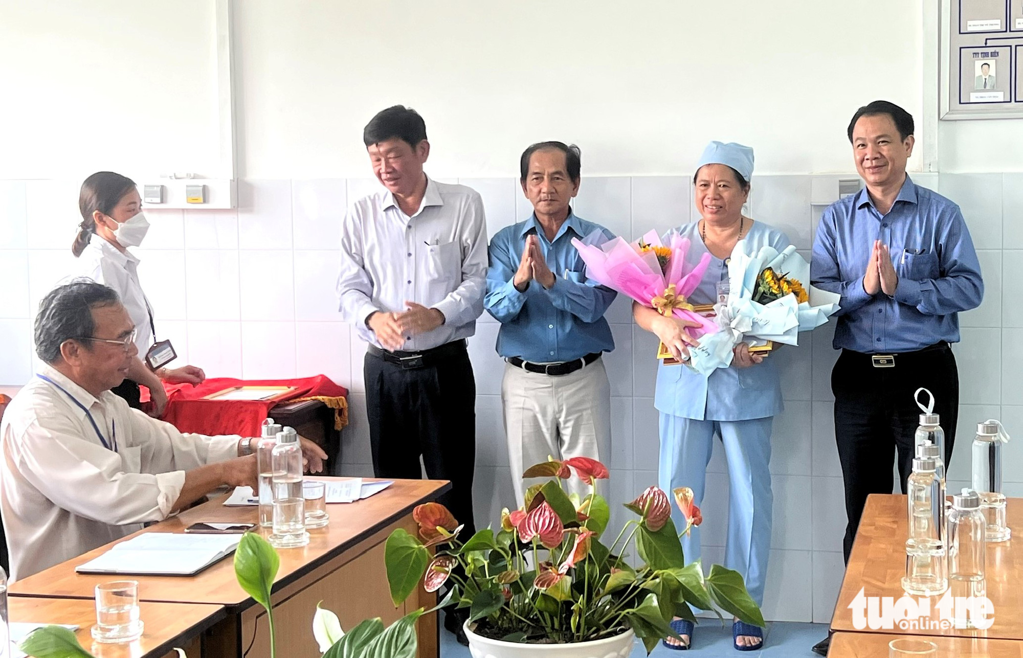 Ông Trần Quang Hiền - giám đốc Sở Y tế tỉnh An Giang (bìa phải) tặng hoa và khen thưởng cho chị Uông Mỹ Hạnh - Ảnh: Sở Y tế cung cấp