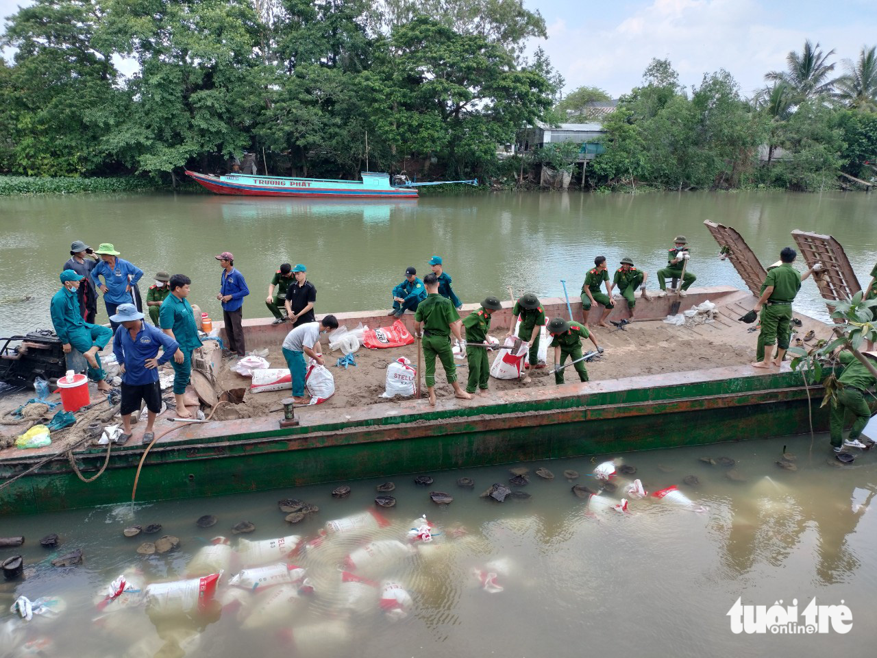 Các lực lượng huyện Cao Lãnh, tỉnh Đồng Tháp thả bao tải cát gia cố đoạn sạt lở trên kênh Cần Lố - Ảnh: TỐNG DOANH