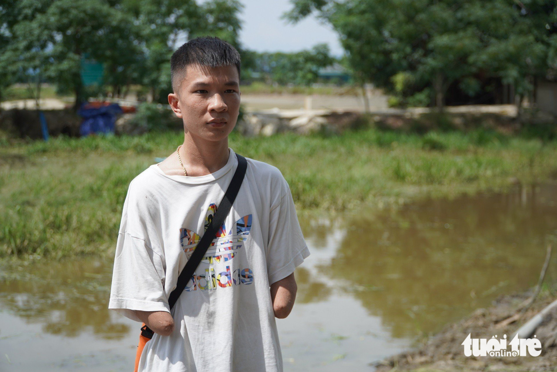 Thanh niên không tay Nguyễn Doãn Mão bên hồ câu do anh đầu tư - Ảnh: LÊ MINH