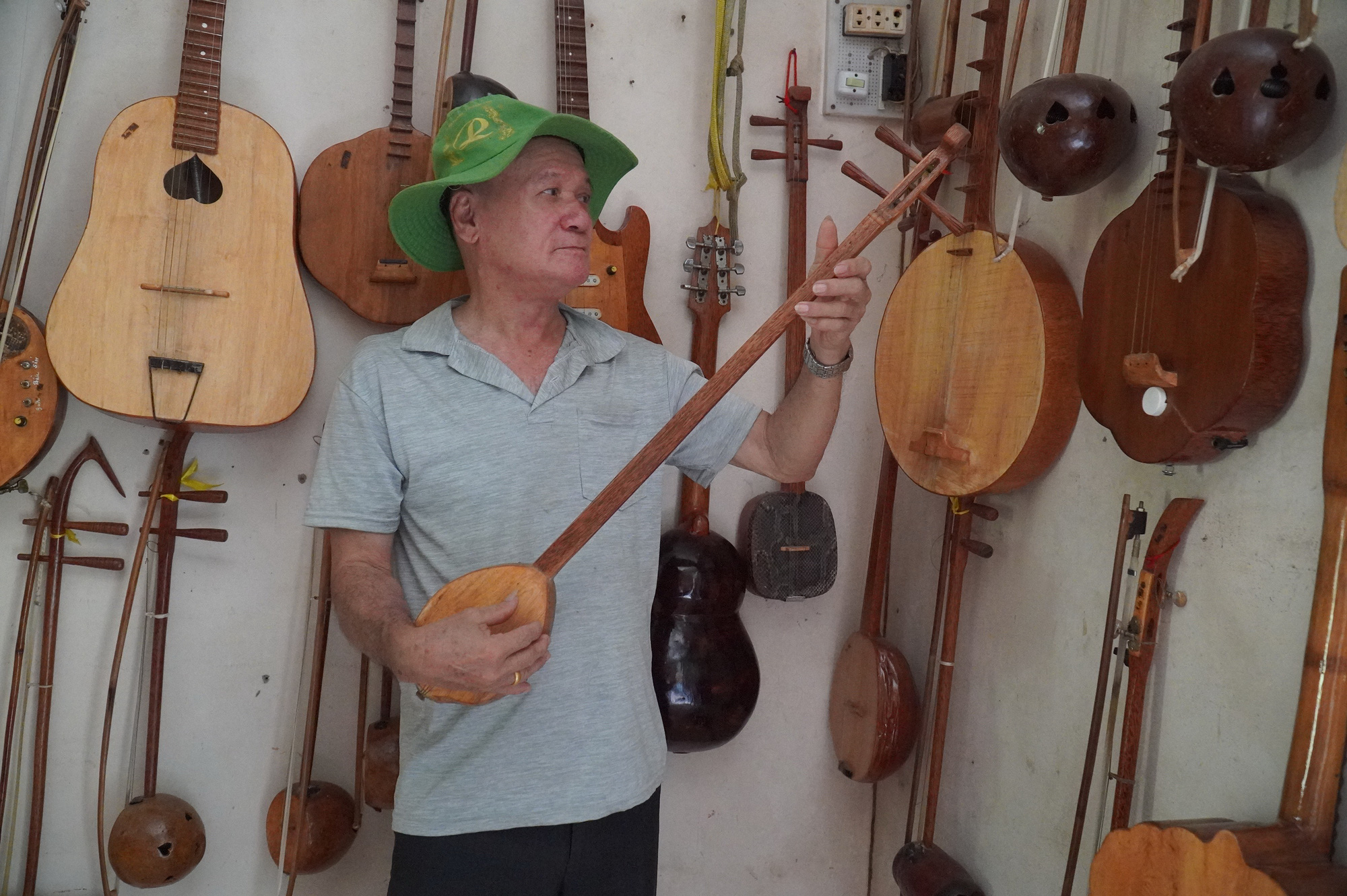 Nghệ nhân Sơn Bá bên những nhạc cụ do ông tự làm từ gỗ dừa - Ảnh: MẬU TRƯỜNG