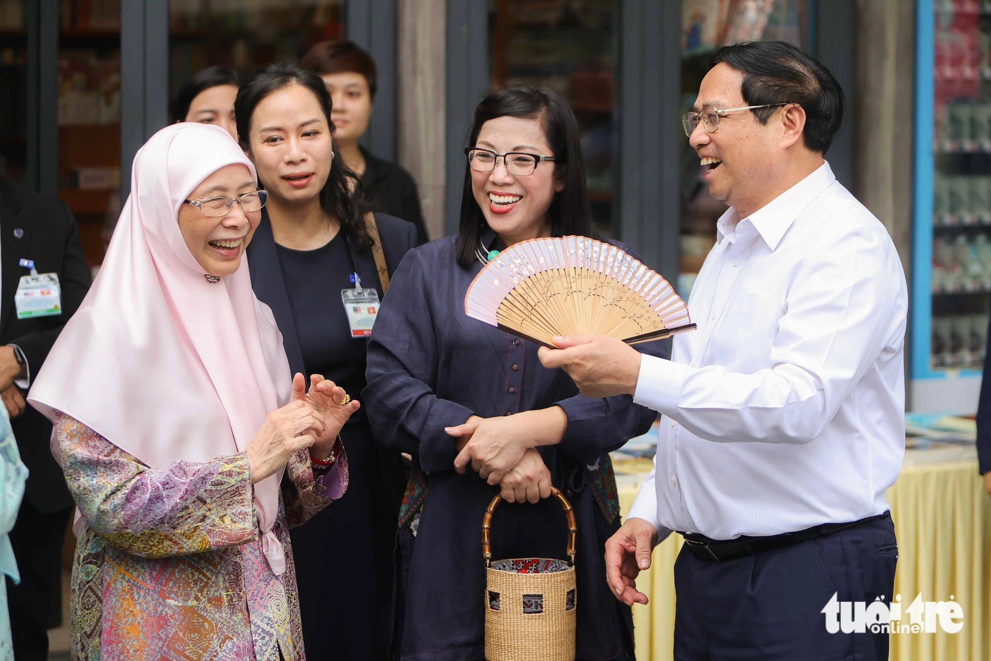 Phu nhân thủ tướng Malaysia bật cười và cảm ơn khi Thủ tướng Phạm Minh Chính dùng quạt để quạt mát cho bà và phu nhân Lê Thị Bích Trân - Ảnh: NGUYỄN KHÁNH