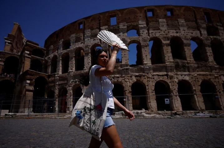 Cô Michelle đến từ Mỹ dùng quạt che nắng khi tham quan Đấu trường La Mã ở Rome, Ý ngày 11-7-2023 - Ảnh: REUTERS