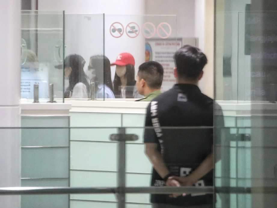Lisa (mũ đỏ) và Jisoo (áo xanh, đeo kính) tại sân bay Nội Bài - Ảnh: LAM GIANG