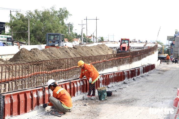 Công nhân đang thi công đổ bê tông bờ tường chân cầu Long Kiểng - Ảnh: LƯU DUYÊN