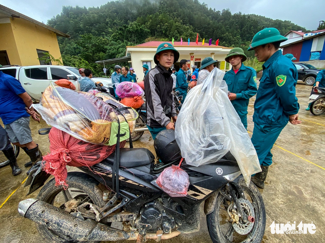 As many places are still mired in deep mud, the functional forces have to use motorbikes to carry blankets, rice, bread, instant noodles and clean water for the people - Photo: CHI TUE