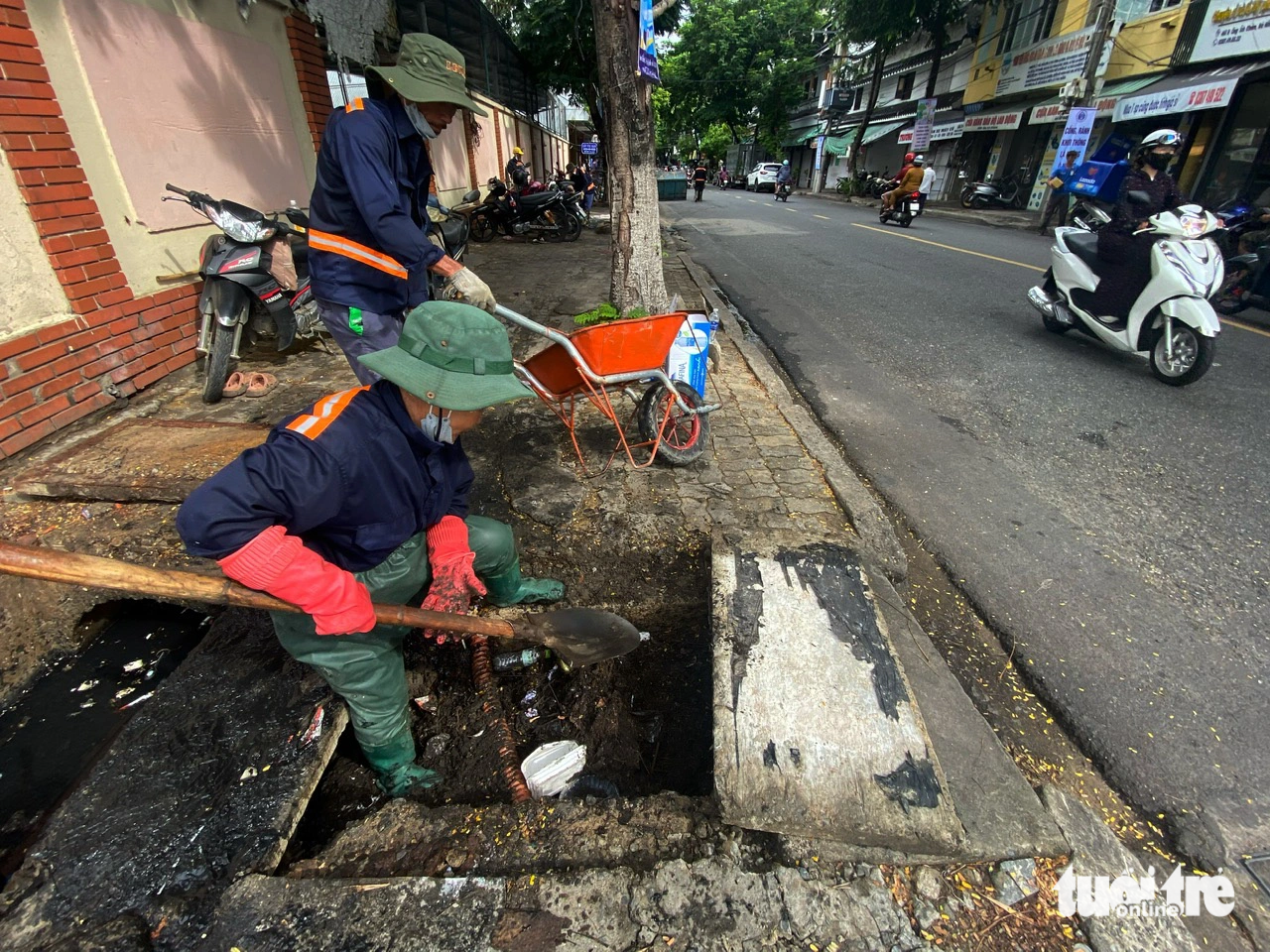 Công nhân Công ty Thoát nước và Xử lý nước thải Đà Nẵng dọn vệ sinh hố thu nước ở các tuyến đường trung tâm - Ảnh: TRƯỜNG TRUNG