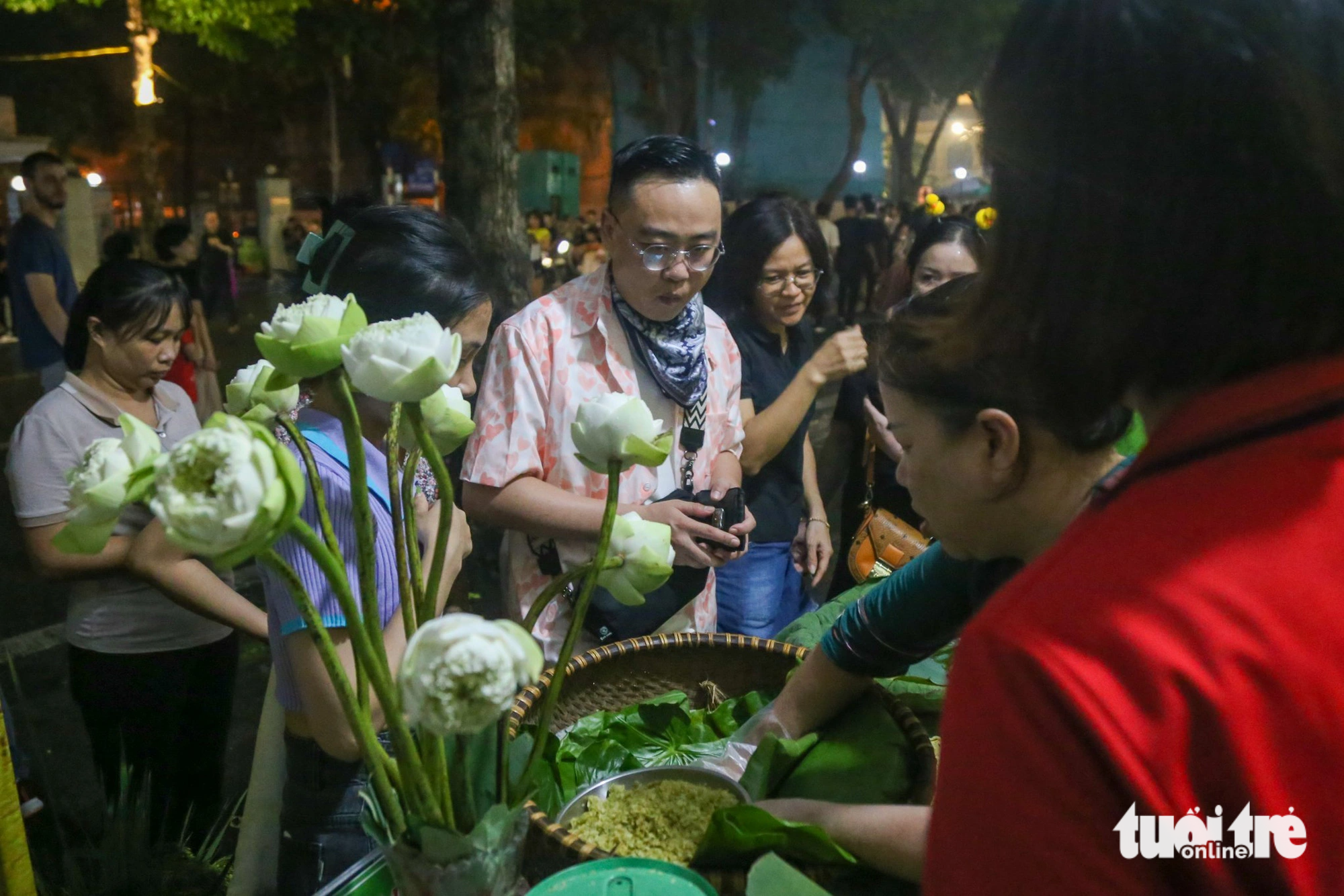 Nhiều du khách thích thú trải nghiệm cốm làng Vòng ngay tại phố đi bộ hồ Hoàn Kiếm trong tiết thu mát mẻ của Hà Nội - Ảnh: HÀ QUÂN