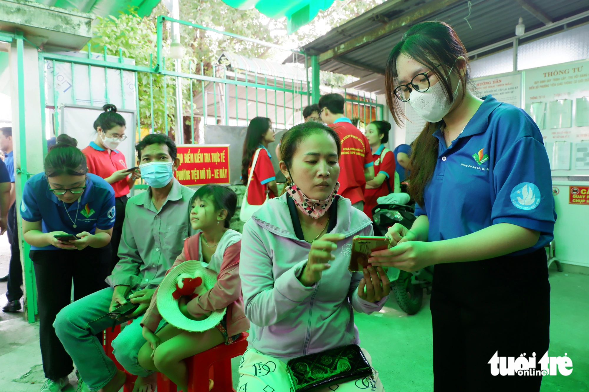 Sinh viên hỗ trợ người dân tại huyện Bình Chánh, TP.HCM khi đến cài đặt mã định danh điện tử -  Ảnh: K.ANH