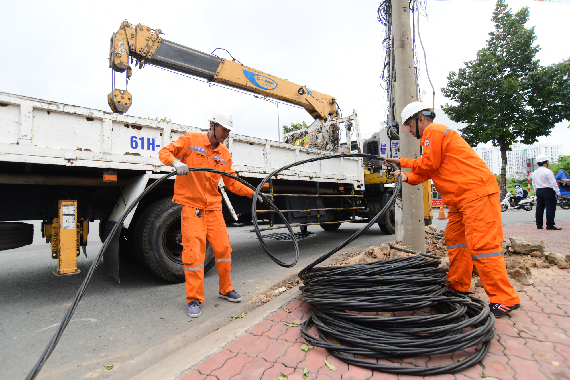 Nhân viên điện lực Thủ Dầu Một, tỉnh Bình Dương thi công kéo cáp hạ thế cấp điện cho khu dân cư đường Hoàng Hoa Thám - Ảnh: QUANG ĐỊNH