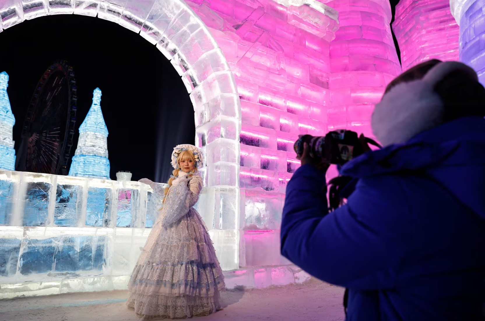 Một nữ du khách hóa trang và tạo dáng chụp hình trước cổng của tòa lâu đài băng - Ảnh: REUTERS