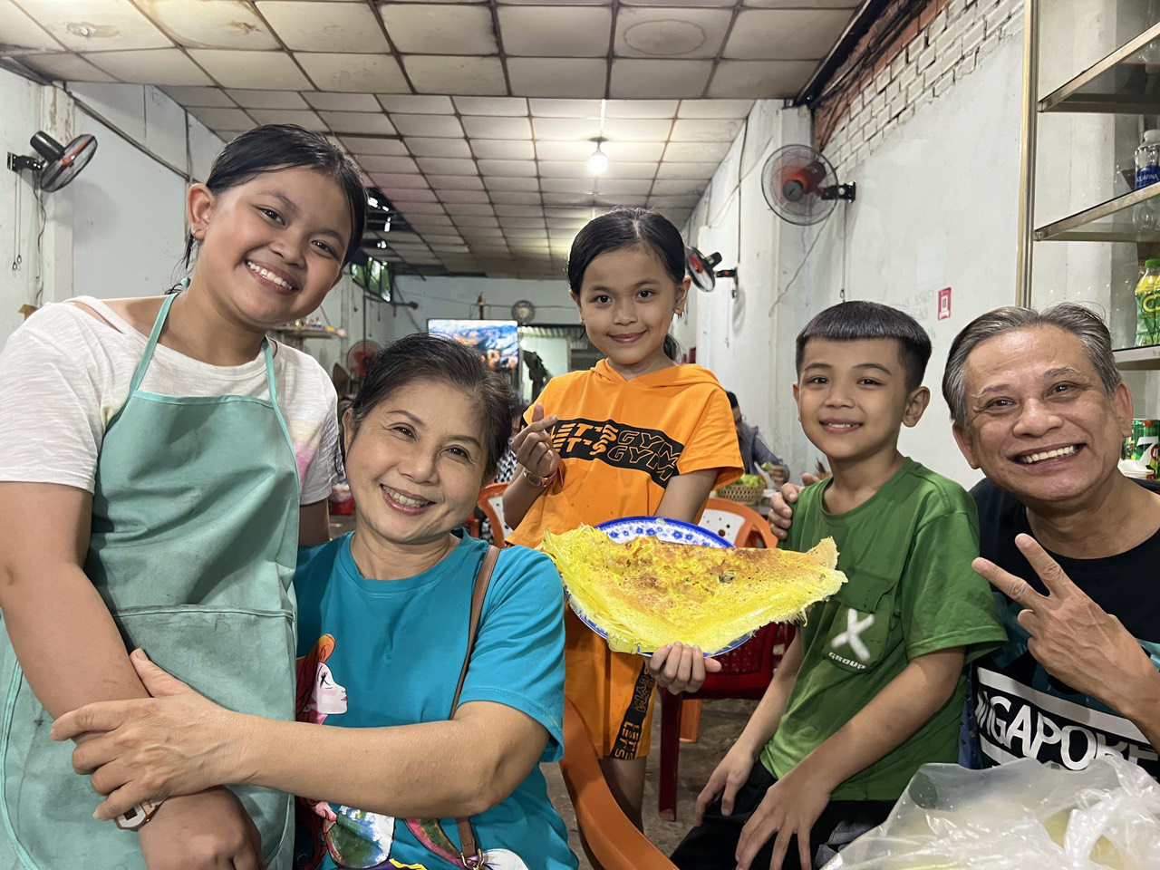 Nghệ sĩ Chí Linh (bìa phải) và Vân Hà (thứ hai từ trái qua) vui vẻ chụp hình cùng các bé mồ côi quán bánh xèo nghèo - Ảnh: HIỀN NHI