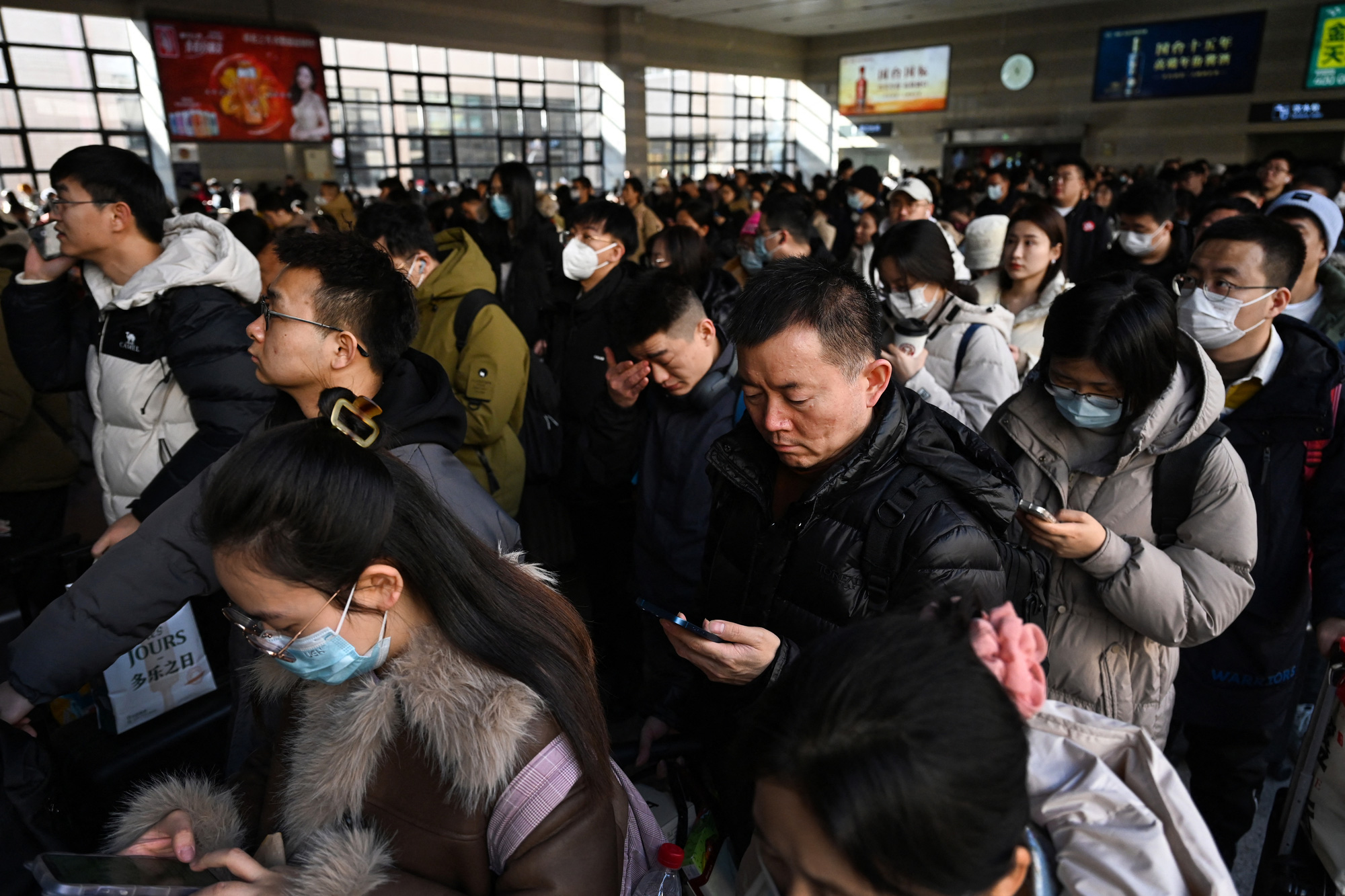 Người Trung Quốc chăm chú với điện thoại thông minh khi chờ xe lửa về quê ăn Tết - Ảnh: AFP