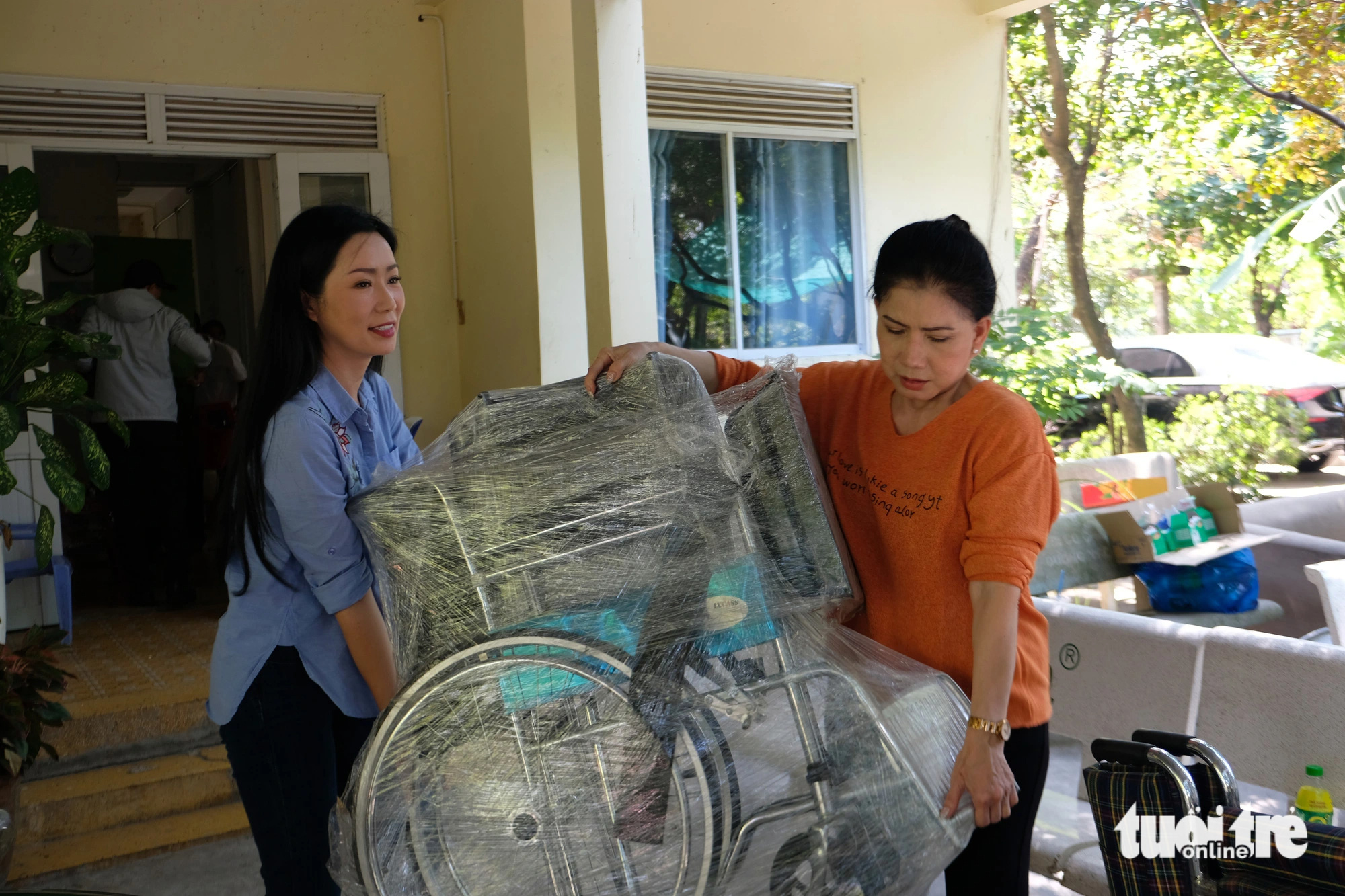 Nghệ sĩ Trịnh Kim Chi (bìa trái) và Phượng Loan phụ khiêng đồ các nghệ sĩ ra xe - Ảnh: LINH ĐOAN
