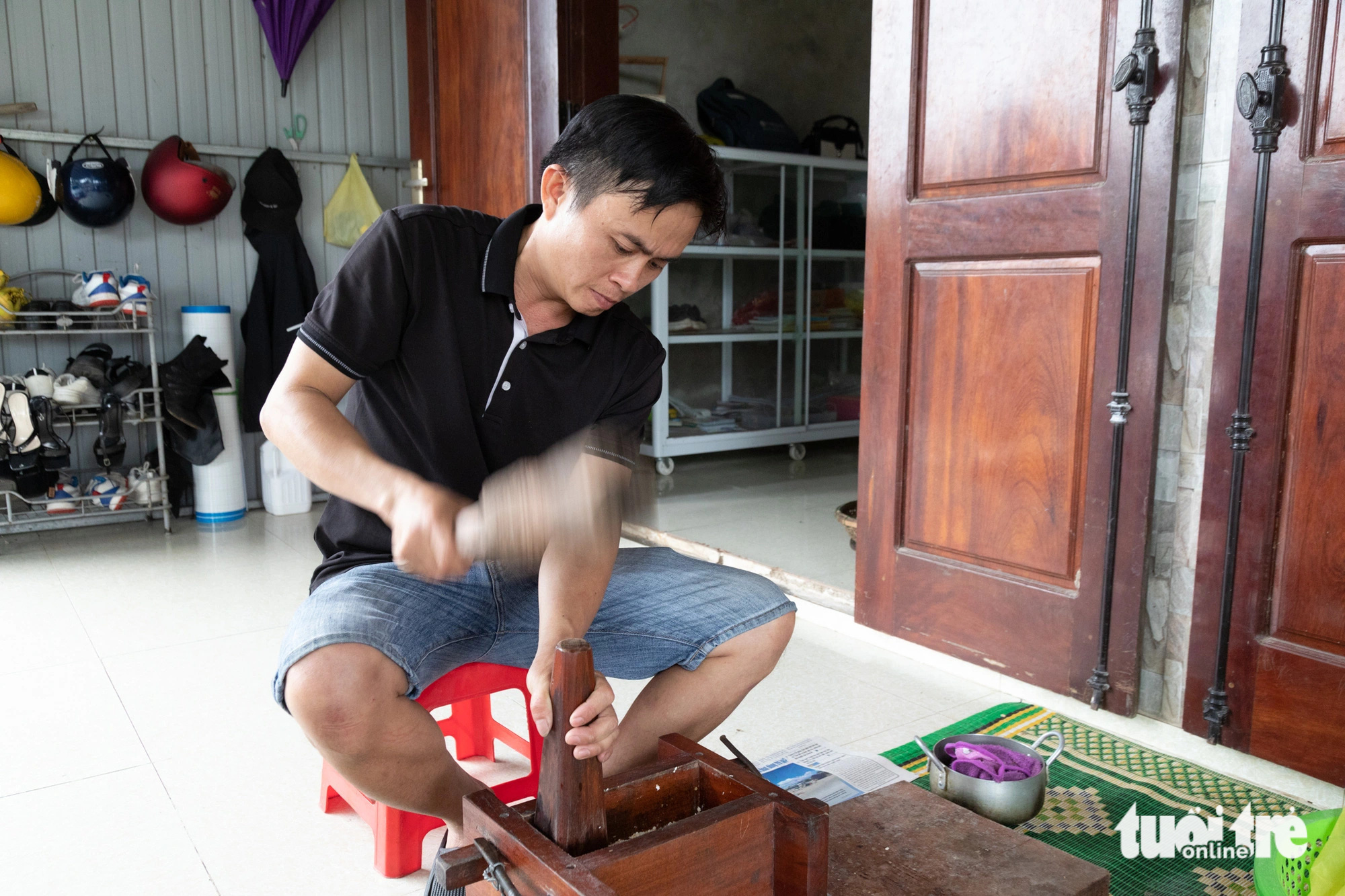 Nguyên liệu được đổ vào khuôn gỗ rồi dùng chày giã mạnh nén thành bánh - Ảnh: HOÀNG TÁO