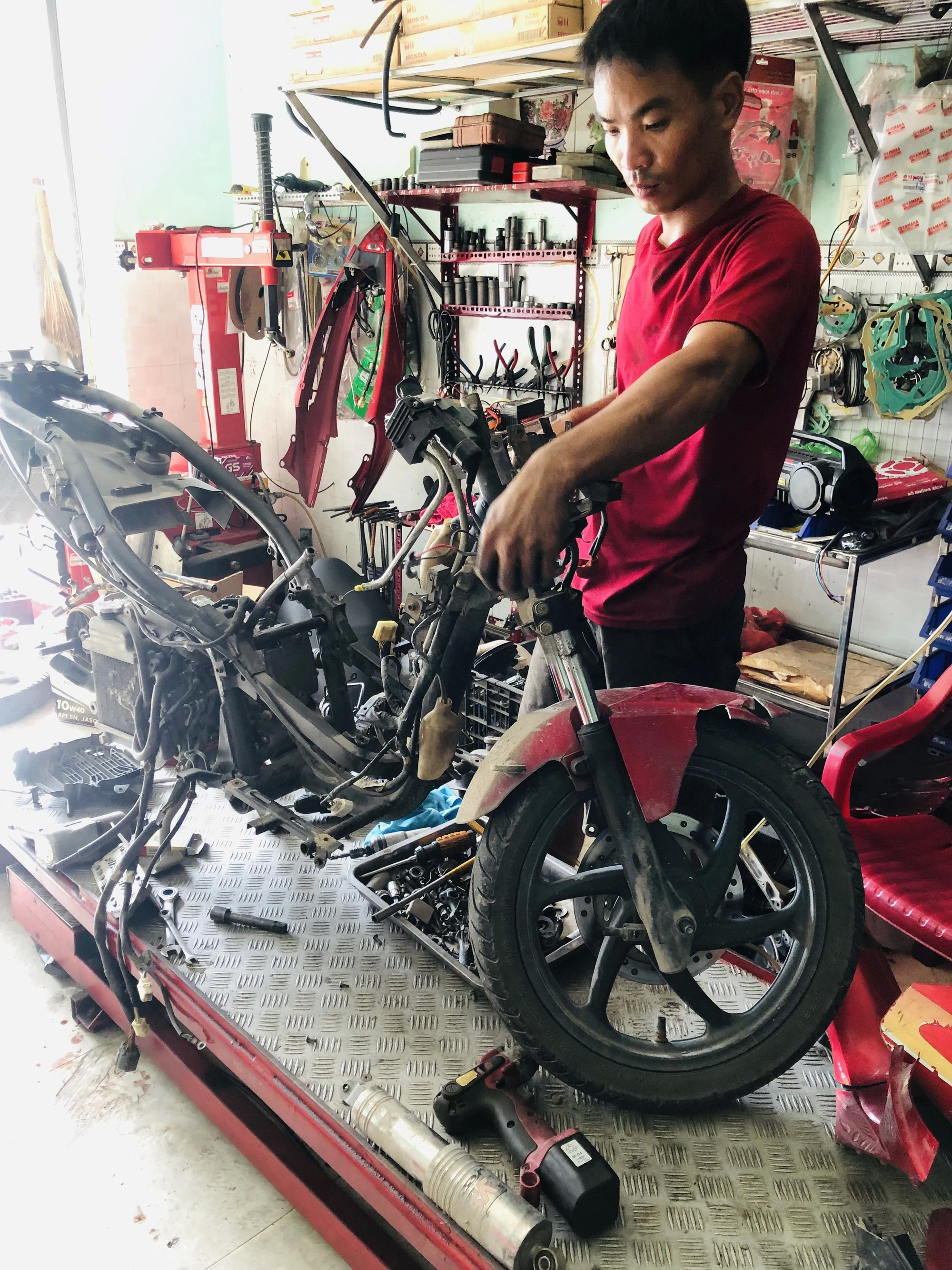 Cuộc thi ảnh Tuổi Xanh: Nghề của ba- Ảnh 1. Bức ảnh chụp người cha của mình đang làm công việc sửa xe - Ảnh: TRỊNH BẢO TRÂM