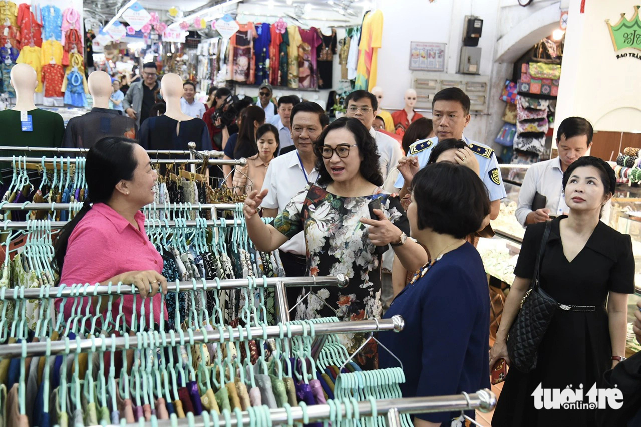 Thứ trưởng Phan Thị Thắng trao đổi về hàng hóa Tết với tiểu thương chợ Bến Thành sáng 6-2 - Ảnh: TỰ TRUNG