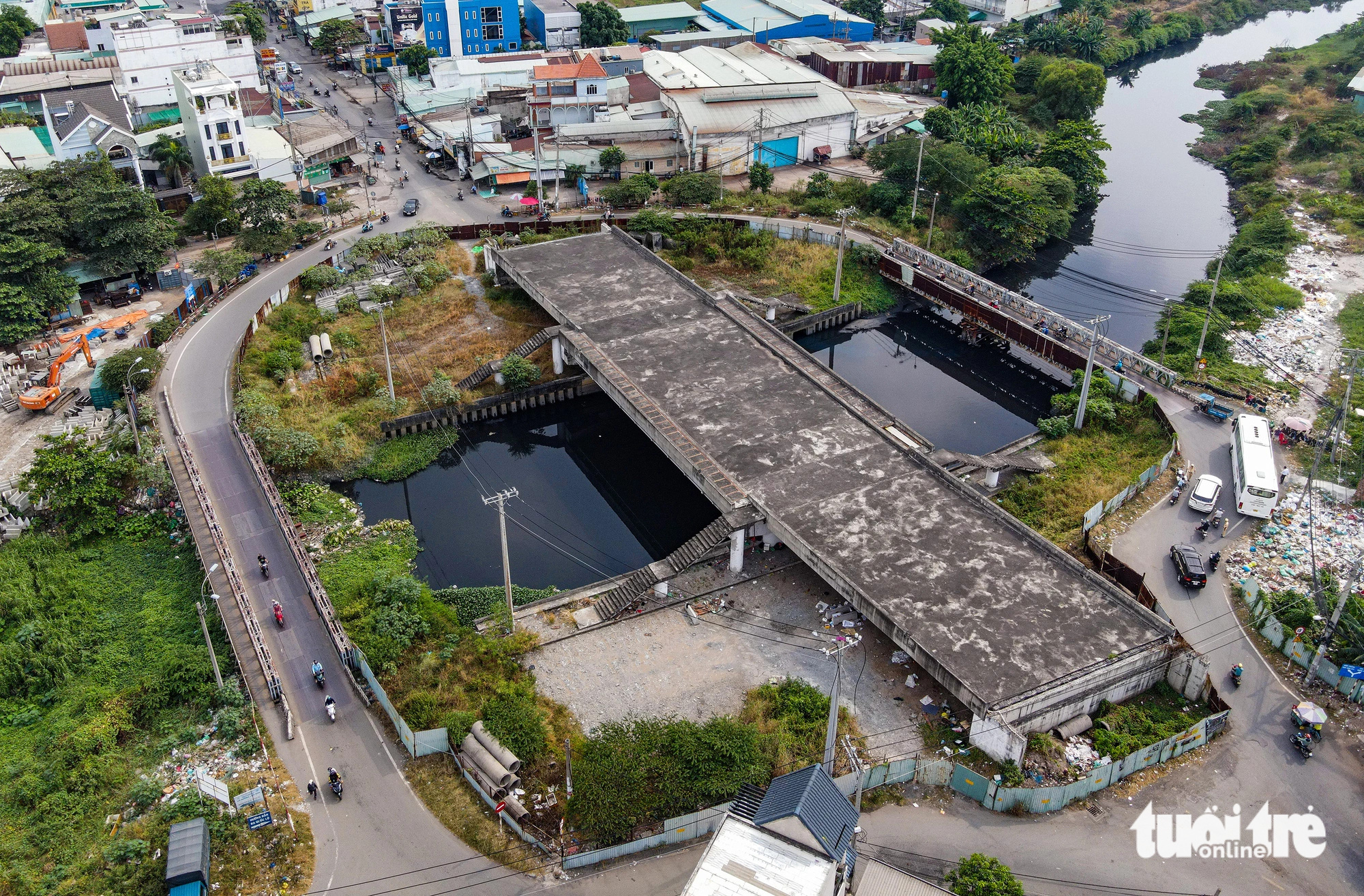 Cầu Tân Kỳ - Tân Quý (quận Bình Tân) bắc qua kênh Tham Lương đang xây dựng dang dở, hai bên là cầu tạm bằng sắt để người dân đi tạm thời - Ảnh: CHÂU TUẤN