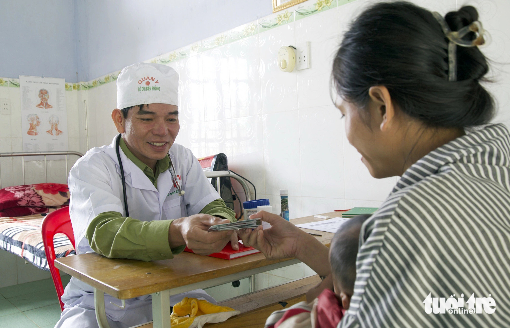 Anh Vũ phát thuốc cho một cháu bé đến khám tại trạm quân y biên phòng - Ảnh: HOÀNG TÁO