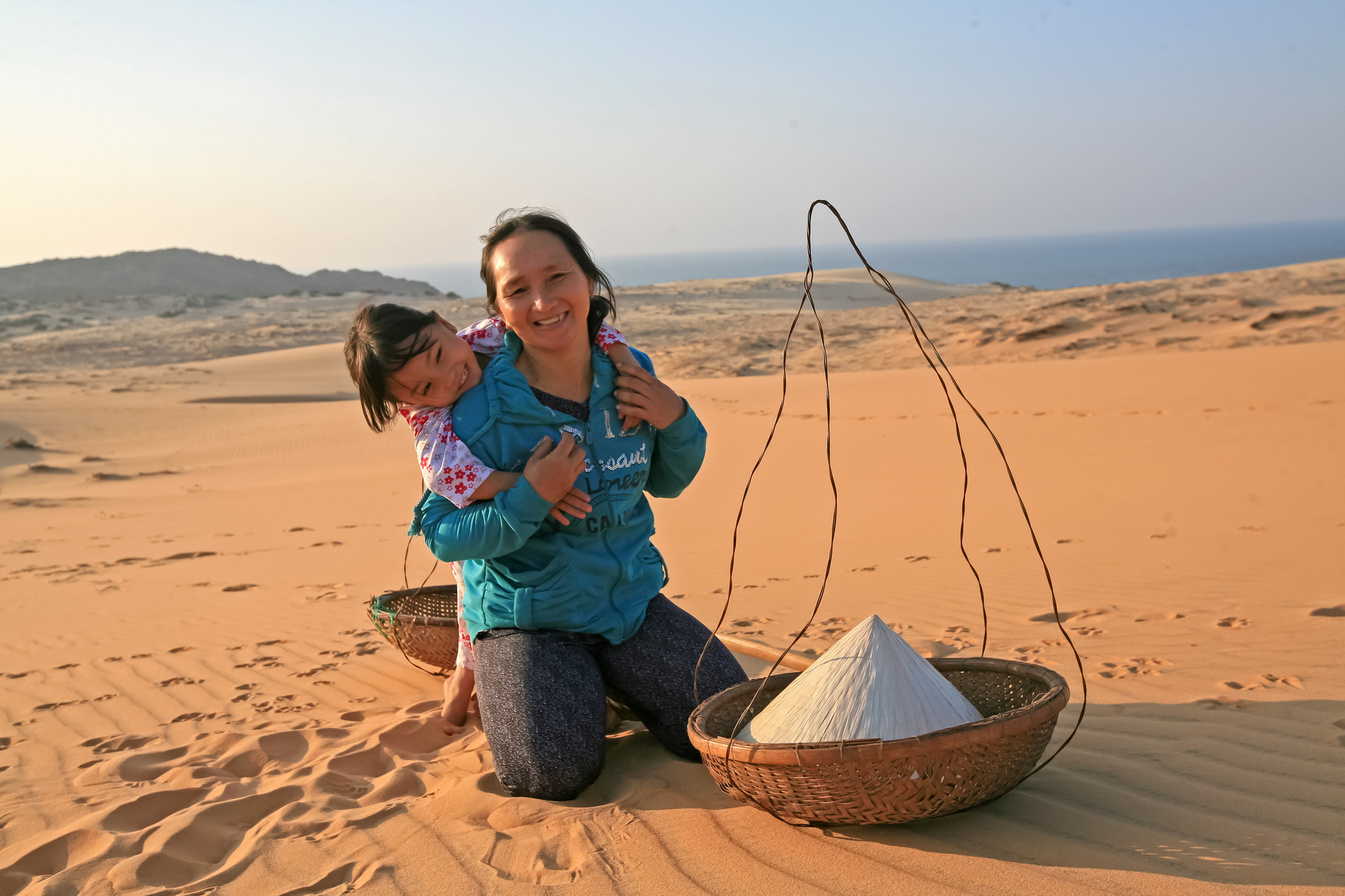 Hai mẹ con nghèo đang ngồi chờ khách thuê làm mẫu chụp ảnh tại đồi cát Phan Thiết, tỉnh Bình Thuận Hai mẹ con nghèo đang ngồi chờ khách thuê làm mẫu chụp ảnh tại đồi cát Phan Thiết, tỉnh Bình Thuận