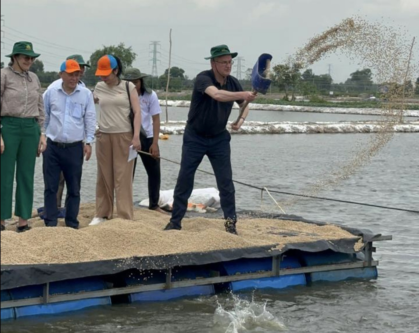 Đan Mạch giúp Việt Nam không mất hàng tỉ USD vì thất thoát, lãng phí nông sản- Ảnh 4. Bộ trưởng Jensen xúc thức ăn cho cá tra tại Tiền Giang - Ảnh: Đại sứ quán Đan Mạch