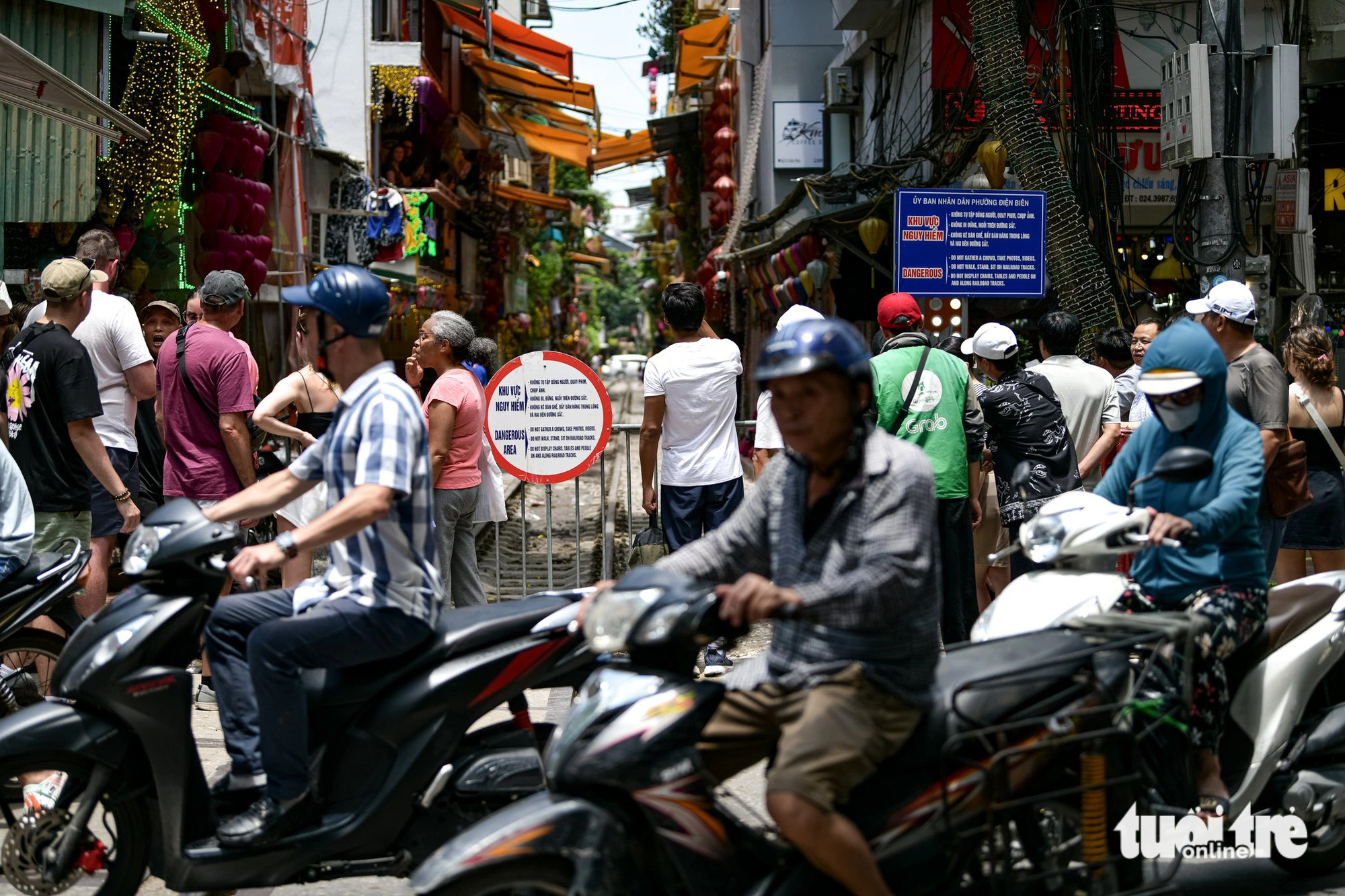 हनोई में रेलवे कैफे स्ट्रीट में प्रवेश करने के लिए बैरिकेड के सामने इकट्ठा हुए विदेशी पर्यटक - फोटो: नाम ट्रान Du khách nước ngoài tập trung đông trước rào chắn vào phố cà phê đường tàu tại Hà Nội - Ảnh: NAM TRẦN