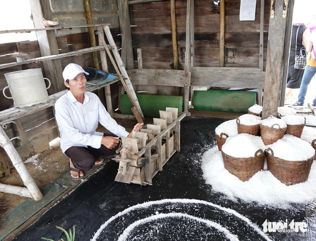 Anh Nguyễn Ngọc Thơ giới thiệu sa quạt bằng tay chuyển nước từ ô ruộng muối này qua ô kia. Anh Thơ cho biết: Xưa kia tát 420m³ nước làm trong 45 phút, nay chỉ việc cắm điện ngồi hút điếu thuốc là xong - Ảnh: T.T.D.