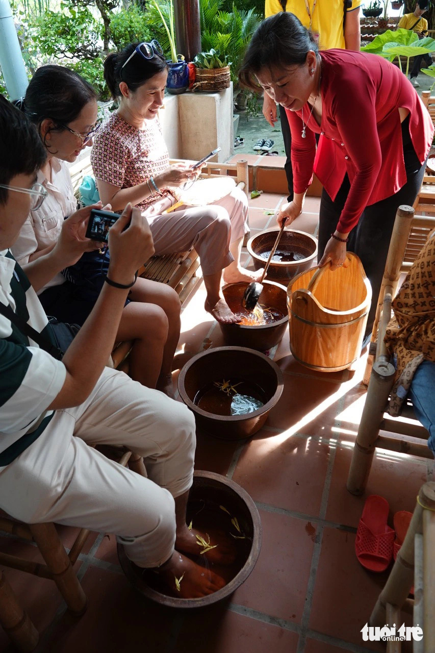 Chị Năm Tuyết phục vụ khách ngâm chân bằng thảo dược và muối Thiềng Liềng - Ảnh: T.T.D.