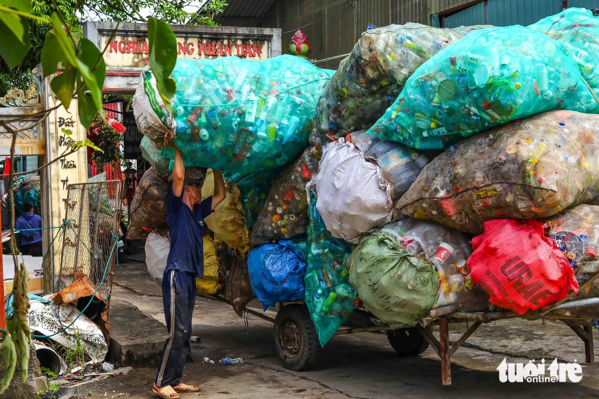 Nếu như Quan Độ (Yên Phong, Bắc Ninh) nổi tiếng với việc “mổ xẻ” xác máy móc, thì Xà Cầu lại là “thủ phủ” của rác thải nhựa. Trong ảnh: Một người đàn ông đang chất những bao tải nhựa lên chiếc xe kéo - Ảnh: THÚY TRANG