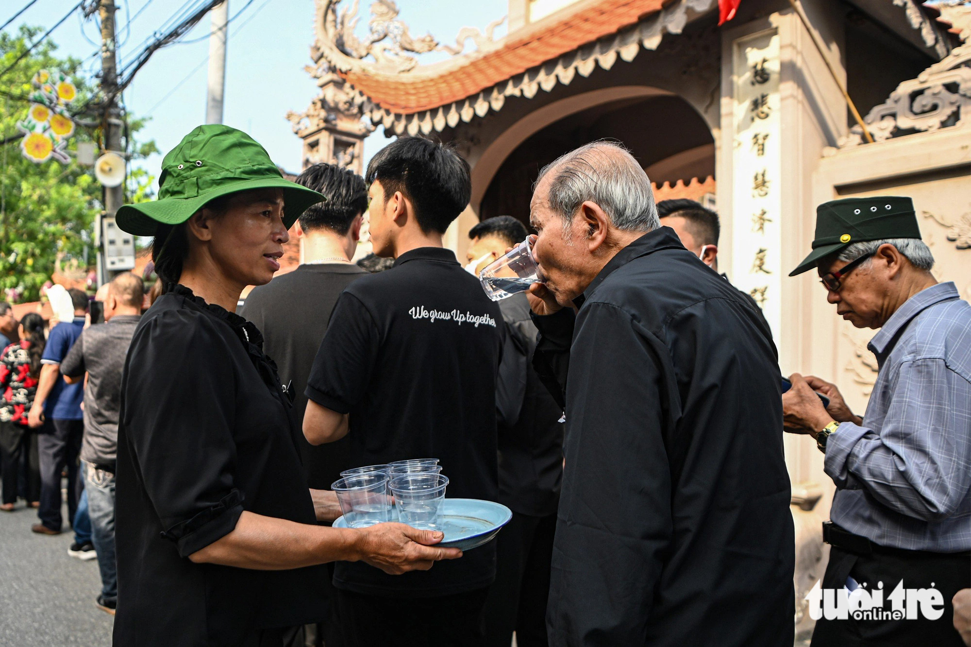 Lai Da-byborna inbjuder folk att besöka generalsekreteraren och njuta av kallt vatten under det varma vädret - Foto: HONG QUANG Người dân xếp quạt cây ra đường, pha nước chanh cho người đến viếng Tổng Bí thư Nguyễn Phú Trọng- Ảnh 1.