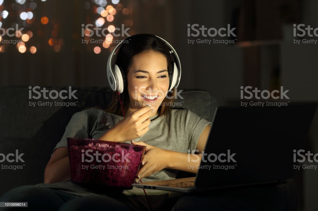 Woman watching online tv in the night Single woman watching online tv in the night sitting on a couch in the living room at home movie stock pictures, royalty-free photos & images