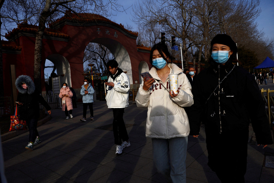 Mọi người đeo khẩu trang để phòng COVID-19 đi bộ trên đường phố Bắc Kinh, Trung Quốc - Ảnh: REUTERS
