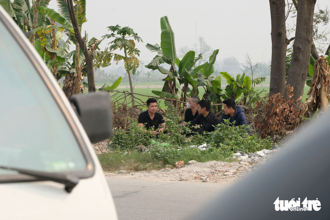 Nhiều tài xế buộc phải ngồi vào bụi cỏ ven đường tránh nắng chờ đăng kiểm do quanh khu vực này không có nhà dân - Ảnh: NGUYÊN BẢO
