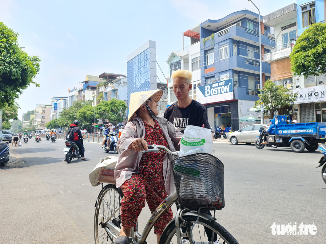 Cô Năm tươi cười, chào tạm biệt thợ tóc Minh Chánh khi đã giúp mình có mái tóc mới cùng phần quà nặng trĩu 