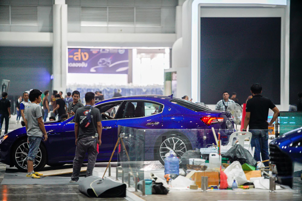 Chiếc Maserati Ghibli đang được chuyển vào triển lãm. Kế bên lấp ló bóng dáng của mẫu SUV Aston Martin DBX màu xanh dương ở gian hàng bên cạnh.