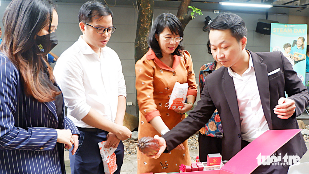 Nguyễn Hồng Huy (phải) giới thiệu chocolate, son môi từ hạt ca cao với khách tham quan - Ảnh: K.ANH
