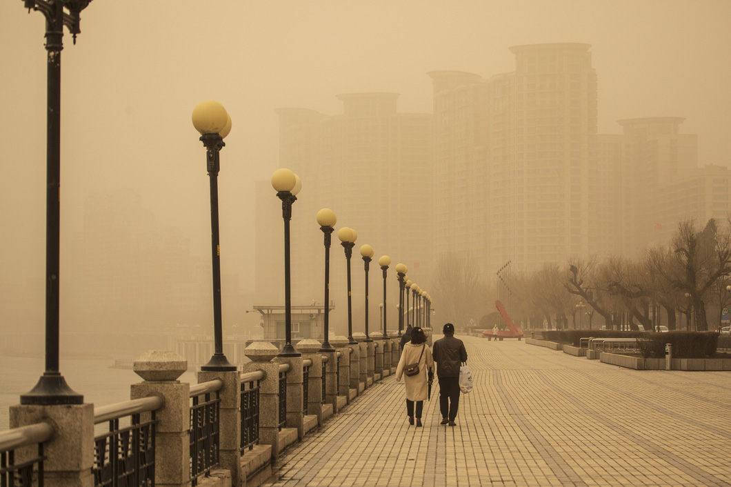 Người dân đi bộ dọc con sông Tùng Hoa, tỉnh Cát Lâm, đông bắc Trung Quốc dưới bụi màu vàng, bầu trời màu vàng sẫm do bão cát ngày 22-3 - Ảnh: AFP