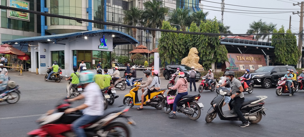 Trong khi lực lượng chức năng khám xét, công nhân mặc đồng phục của công ty Tân Hiệp Phát vẫn được qua cổng công ty - Ảnh: BÁ SƠN