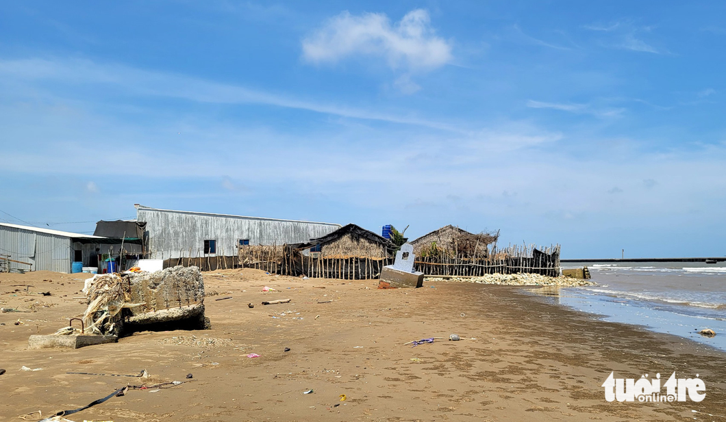 Ngôi mộ hỏng chân do sóng biển, nằm kế căn nhà của một hộ dân được kè bằng tràm - Ảnh: CHÍ HẠNH