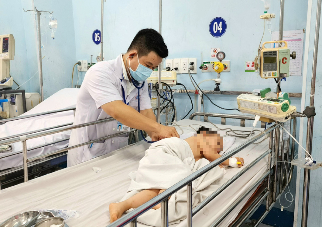 Bác sĩ Dư Tuấn Quy đang khám cho trẻ mắc bệnh tay chân miệng - Ảnh: T.PHƯƠNG