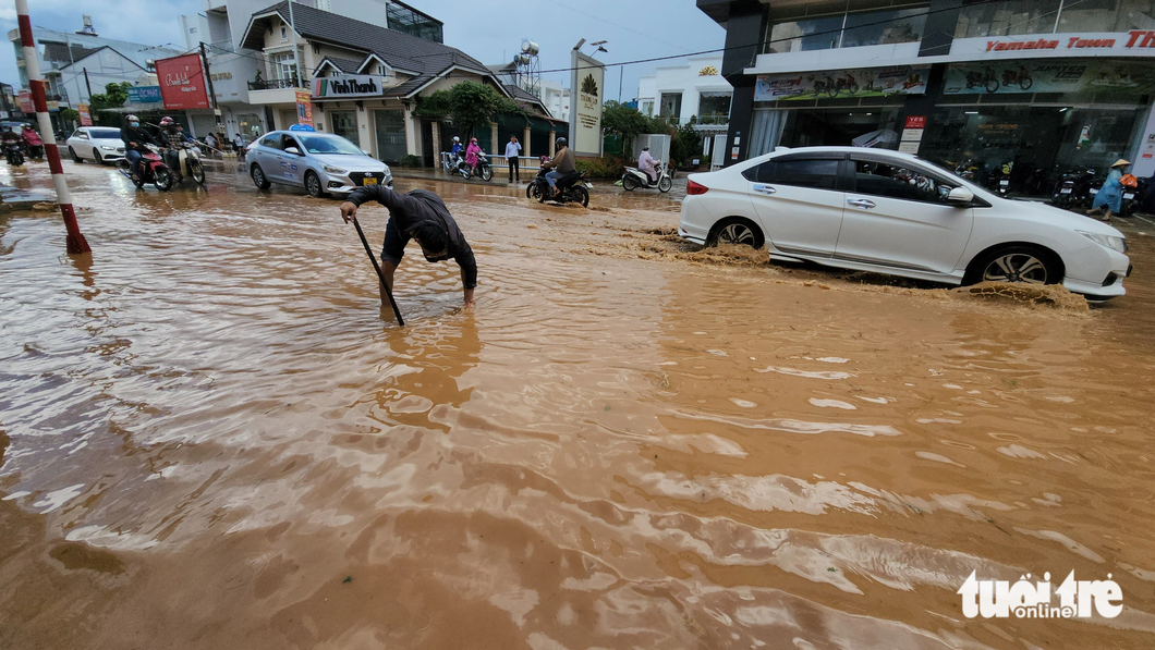 Người dân thông các lỗ thoát nước trên đường Phan Đình Phùng đang bị ngập - Ảnh: M.V.