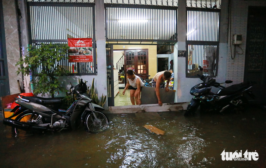 Người dân phải "đắp đê" ngăn nước tràn vào nhà. Ghi nhận trên đường số 6 (từ quốc lộ 13 chạy vào khoảng 200m, thuộc phường Hiệp Bình Phước, TP Thủ Đức) - Ảnh: CHÂU TUẤN